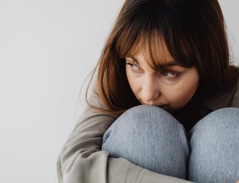 pexels-karola-g-7273368 kobieta obejmująca podciągnięte kolana i patrząca w bok
